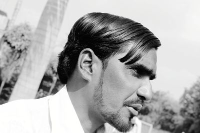 Man looking away against trees and sky