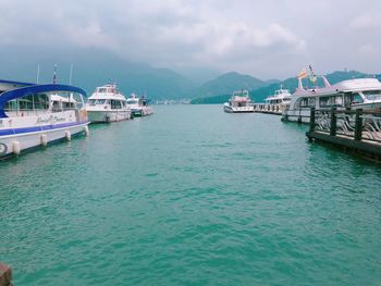 View of boats in sea against cloudy sky