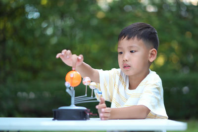 Close-up of cute boy playing with model on table in park