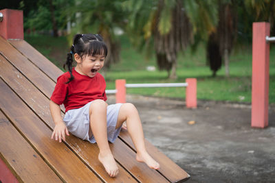 Side view of boy sitting on slide at park