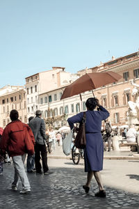 Rear view of people walking on street against buildings