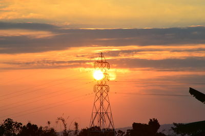 Low angle view of silhouette electricity pylon against sky during sunset