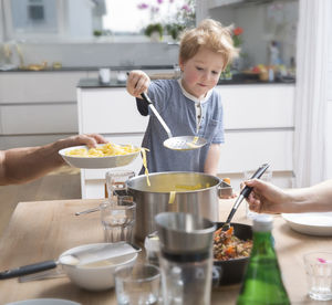 Proud little boy serving pasta in kitchen