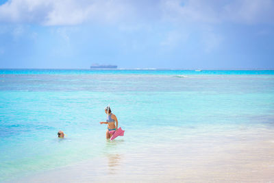 Woman talking to friend swimming in sea against sky