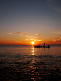 Silhouette boat in sea against sky during sunset