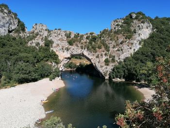 Scenic view of river amidst trees against clear blue sky