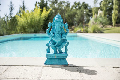 Close-up of ganesha statue by swimming pool against trees