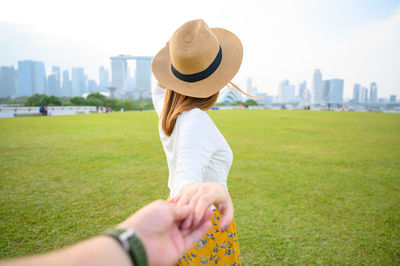 Cropped image of man holding woman hand standing on land