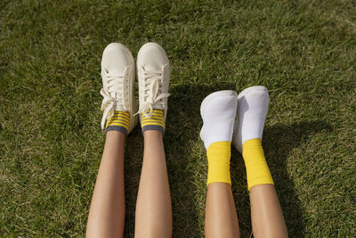 Girls wearing white shoes relaxing on grass at park