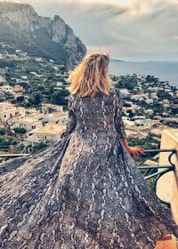 Rear view of woman looking at cityscape against sky