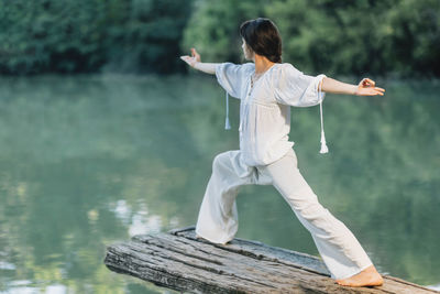 Yoga by the lake - young woman practicing warrior 2 pose or virabhadrasana ii
