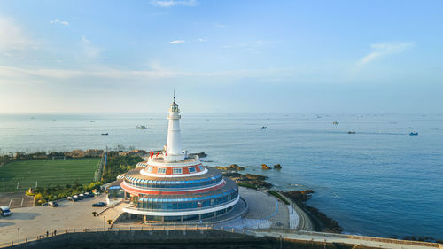 Lighthouse by sea against sky