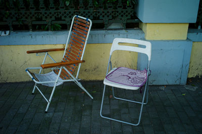 High angle view of empty chairs and tables on sidewalk by building