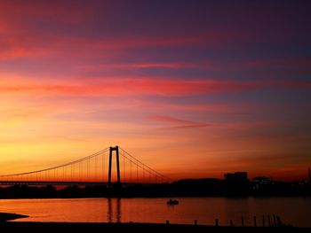 Silhouette bridge over river against sky during sunset