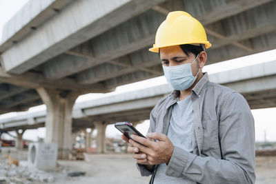 Man holding mobile phone while standing at camera