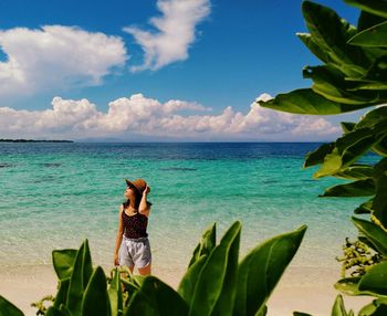 Young woman walking on shore at beach against sky