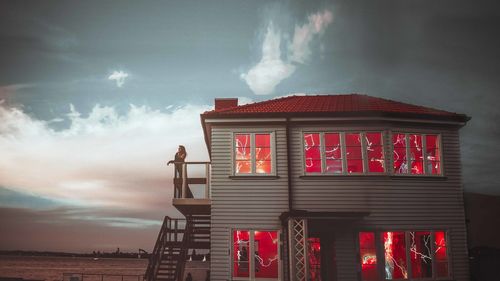 Low angle view of person standing by building against sky