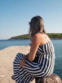 Side view of woman looking at sea against clear sky