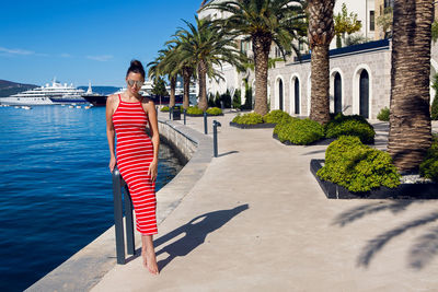 Woman with sunglasses stands on the pier among the palm trees