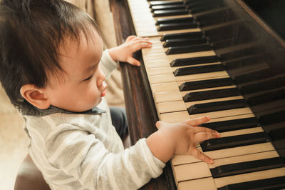 Cute boy playing piano at home