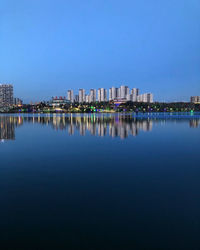 Reflection of buildings in lake against blue sky