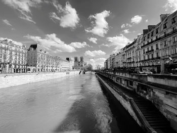 Bridge over canal amidst buildings in city against sky