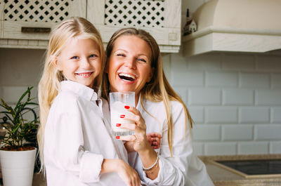 Portrait of happy mother and daughter in kitchen at home