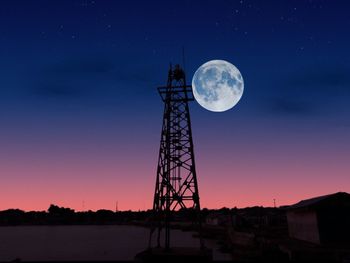 Low angle view of silhouette cranes against sky at night