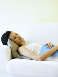 Woman with book sleeping on sofa at home