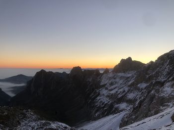 Scenic view of snowcapped mountains against clear sky during sunset