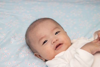 Portrait of cute baby lying on bed