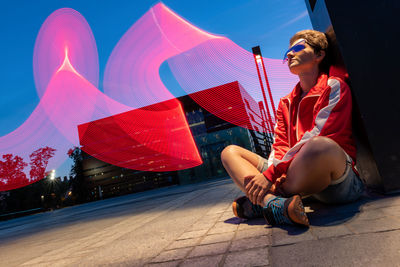 Portrait of young woman sitting outdoor on a ground on a long exposure. freeze light concept