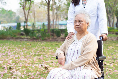 Midsection of female doctor with senior woman sitting on wheelchair