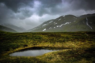 Scenic view of mountains and lake against cloudy sky