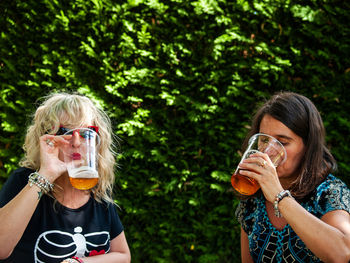 Women drinking beer in glass against plants