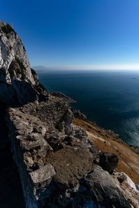 Rock formations by sea against clear blue sky