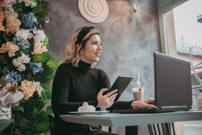 Young woman using phone while sitting on table