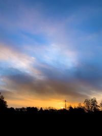 Silhouette trees on field against sky at sunset