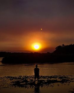 Silhouette man standing on beach against sky during sunset