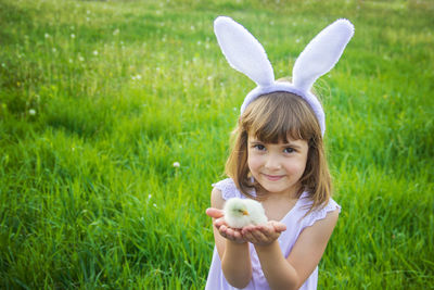 Portrait of woman with rabbit on grassy field