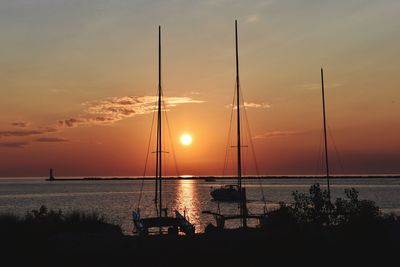 Silhouette of sailboat in sea during sunset