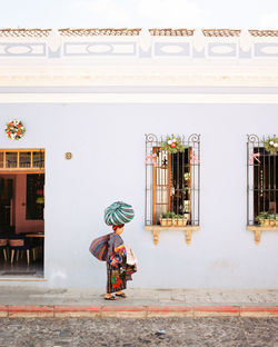 Rear view of woman walking on building in city