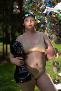 Portrait of young woman in a cap against the background of cd disks holds a mannequin in her hands