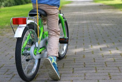 Low section of boy riding bicycle on footpath