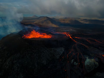 Scenic view of erupting lava on mountain during sunset