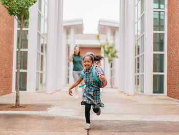 Young millennial mother sending daughter off back to school