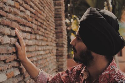 Portrait of young man looking at brick wall