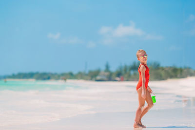 Woman standing on beach against sky