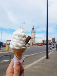 Midsection of woman holding ice cream cone against sky