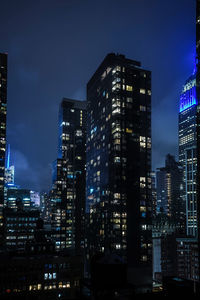 Low angle view of illuminated cityscape against sky at night